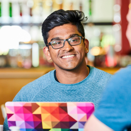Student smiling with a colourful laptop in the foreground